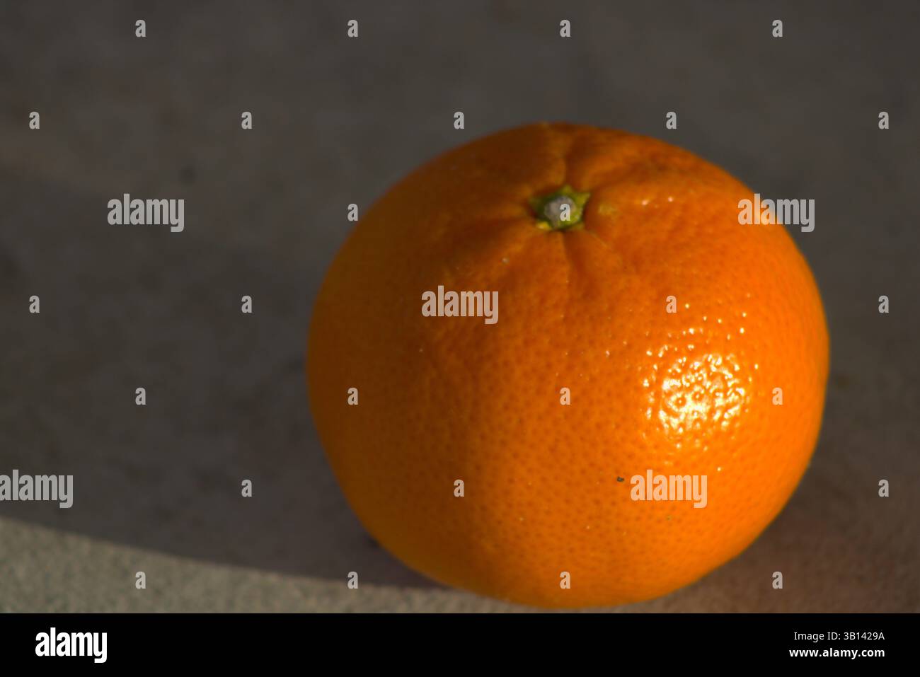 miniature orange sitting on pavement Stock Photo