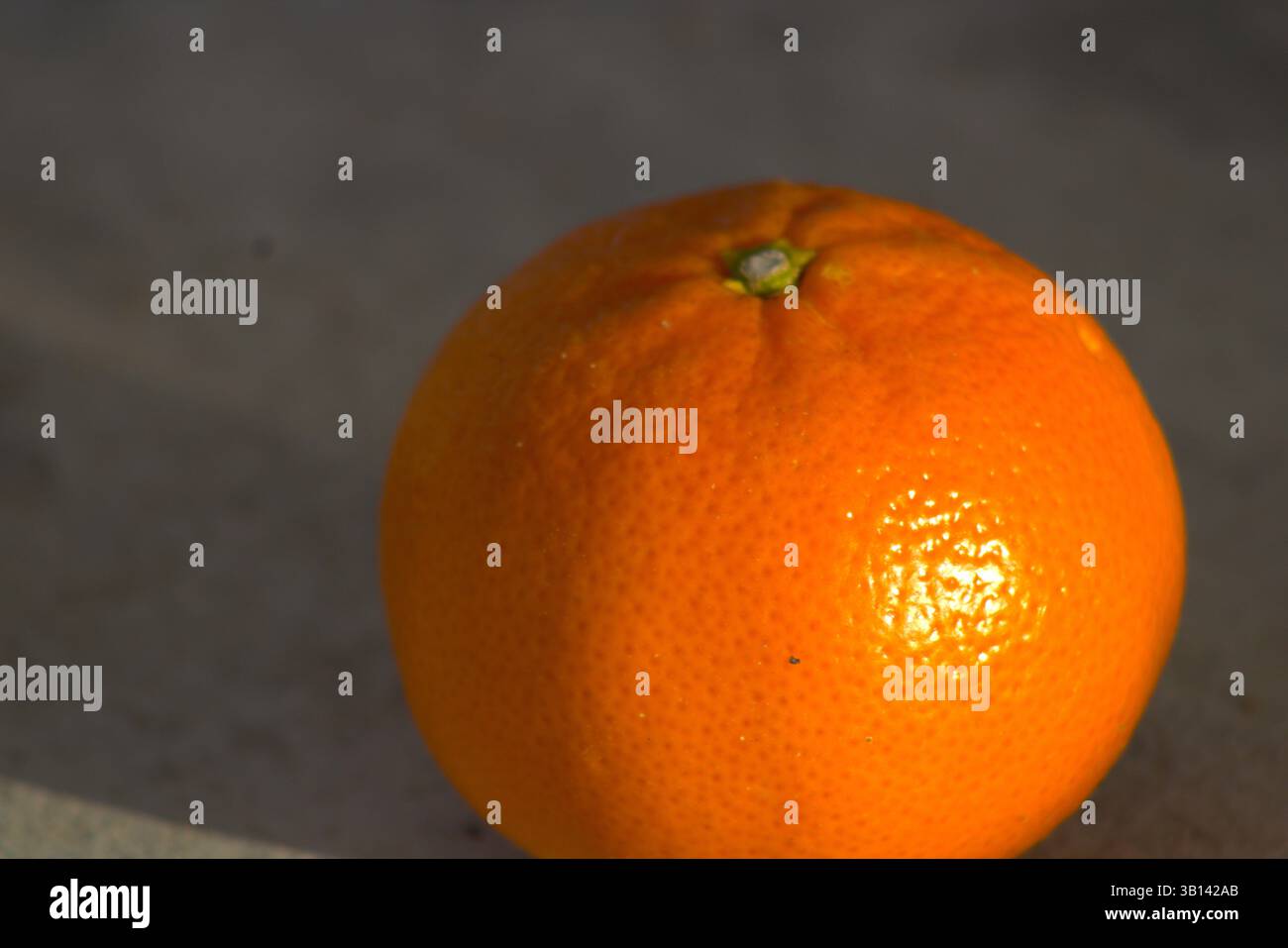 miniature orange sitting on pavement Stock Photo