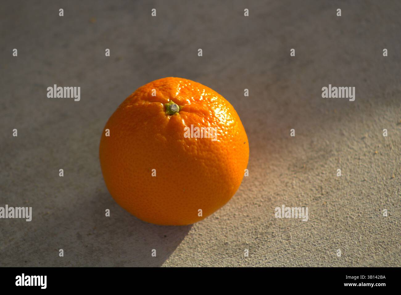 miniature orange sitting on pavement Stock Photo