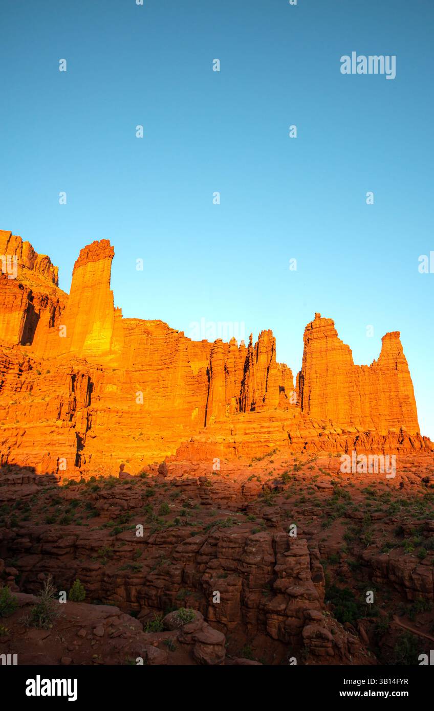 The last rays of sunlight creep up the towering walls of the Fisher Towers, Utah Stock Photo