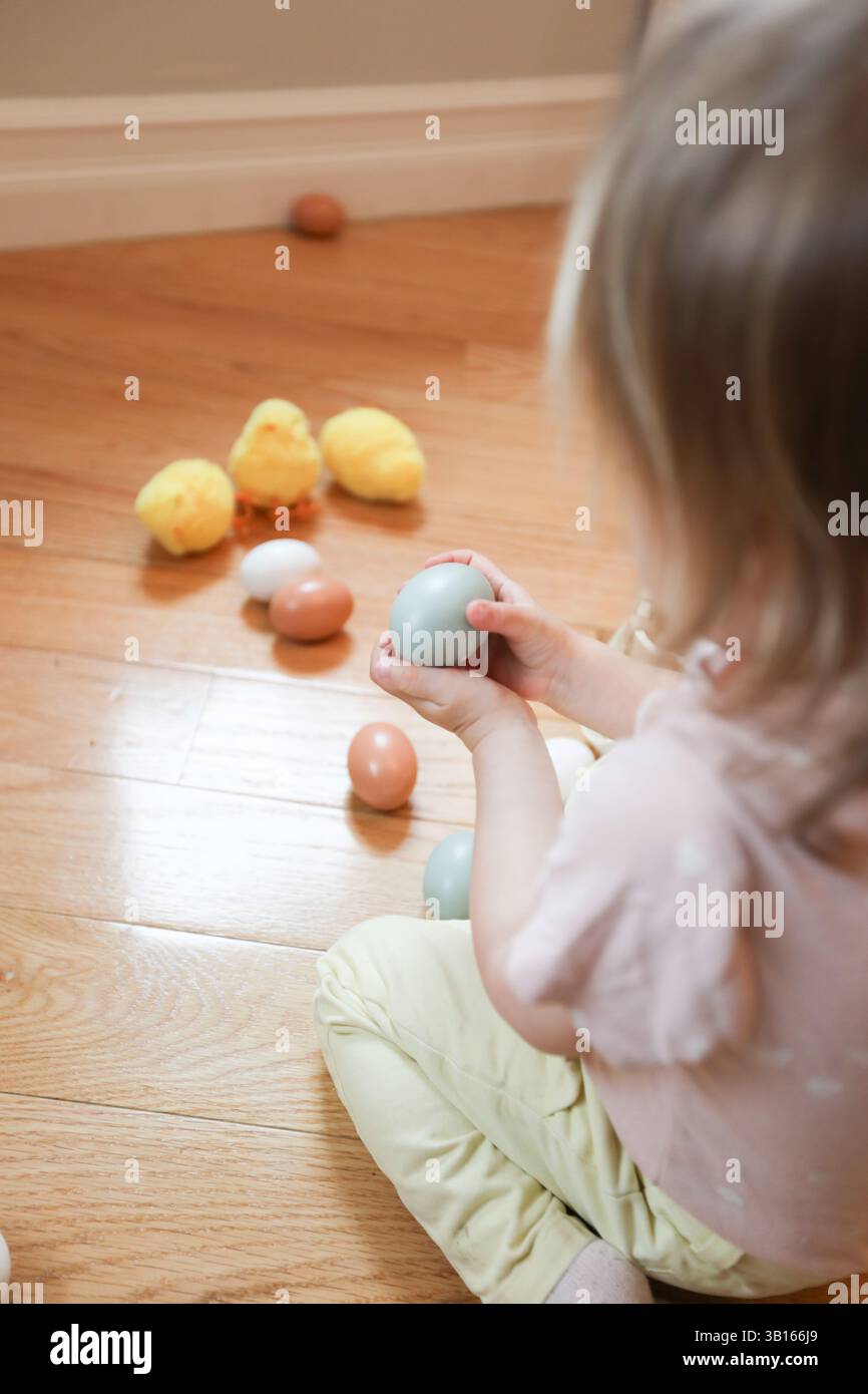 Two year old holding blue chicken egg with easter decoration Stock Photo