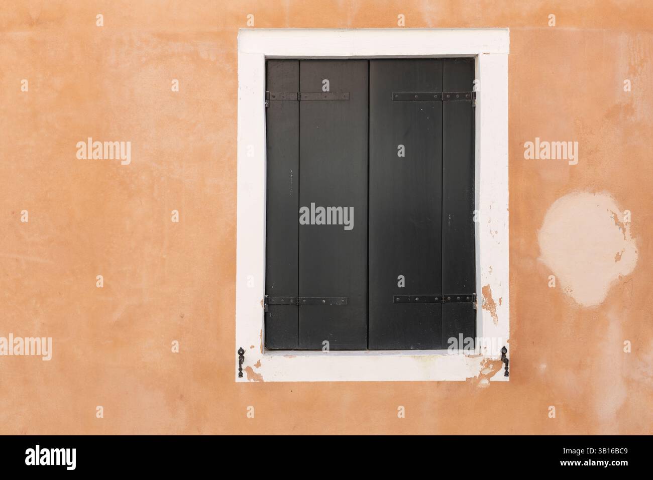 Closed Dark Shutters on Orange Wall Stock Photo