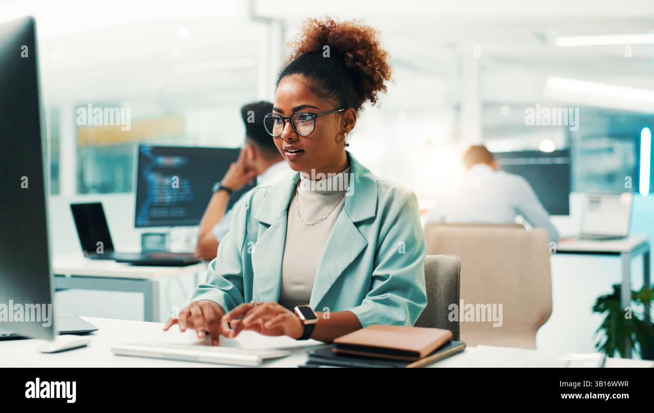 Programmer, woman and typing on computer in office for software development, code debugging and testing app. African person, employee and technology Stock Photo