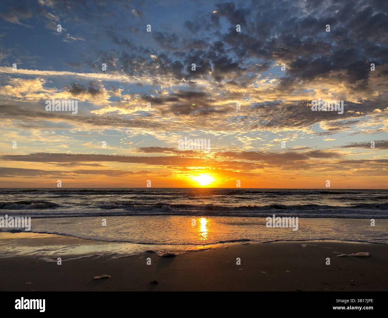 Sunrise on Amelia Island with colorful sky, dramatic clouds, small waves and the sun's reflection in the water. Florida, USA. - Smartphone Captured Stock Image