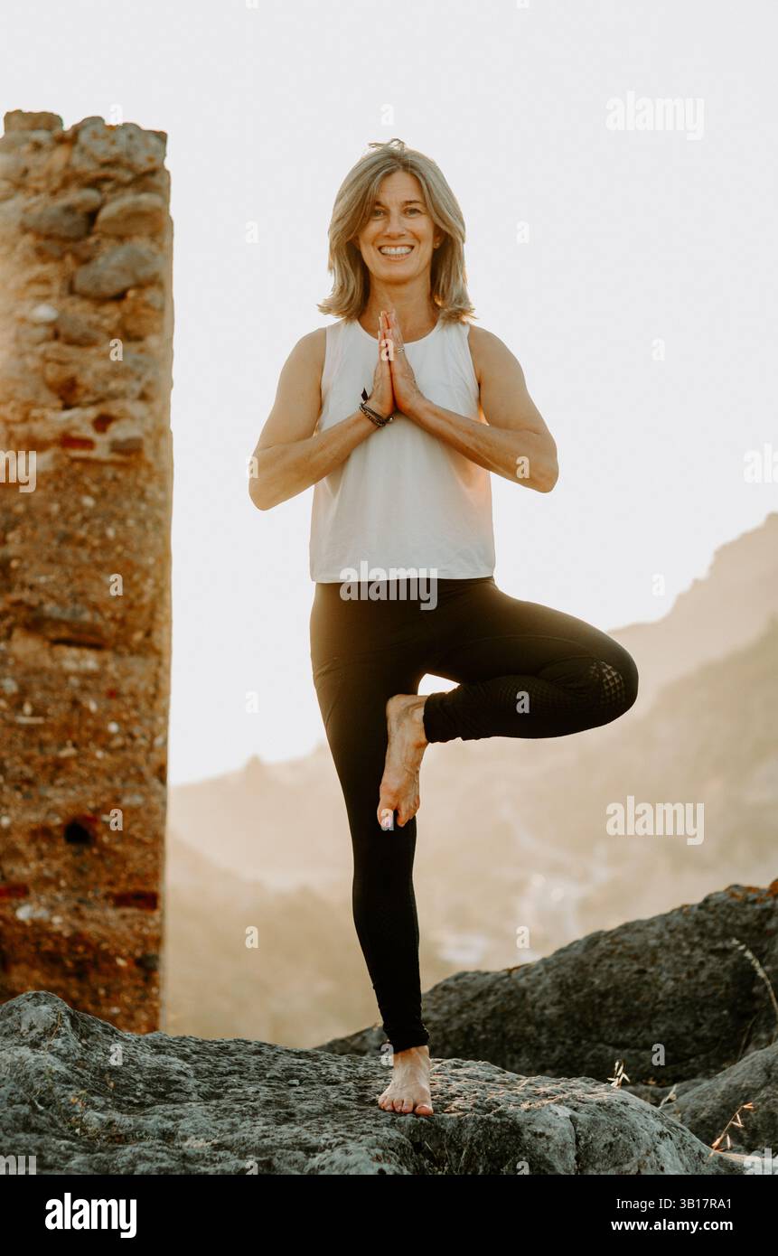 Woman practicing yoga tree pose on a mountain at sunset Stock Photo - Alamy