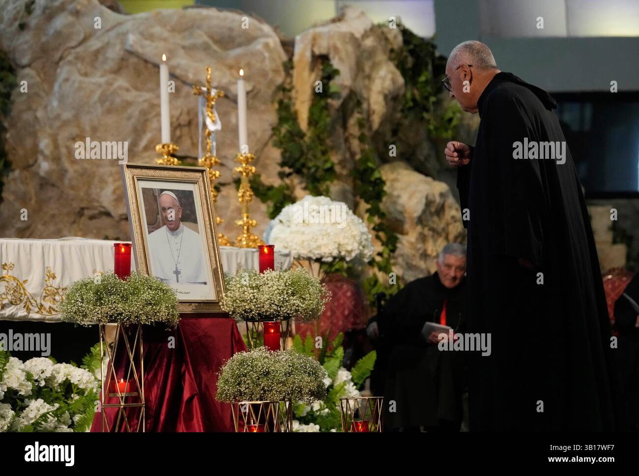 A priest prays in front of a portrait of the late Pope Francis during a ...