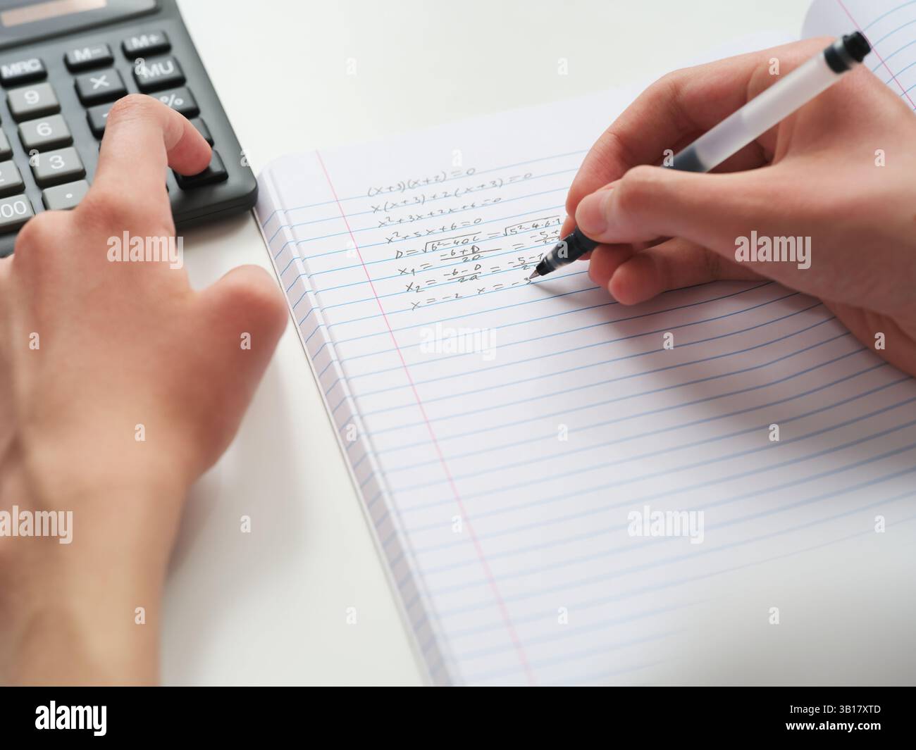 A student doing math in a notebook using a calculator. Close up. Stock Photo