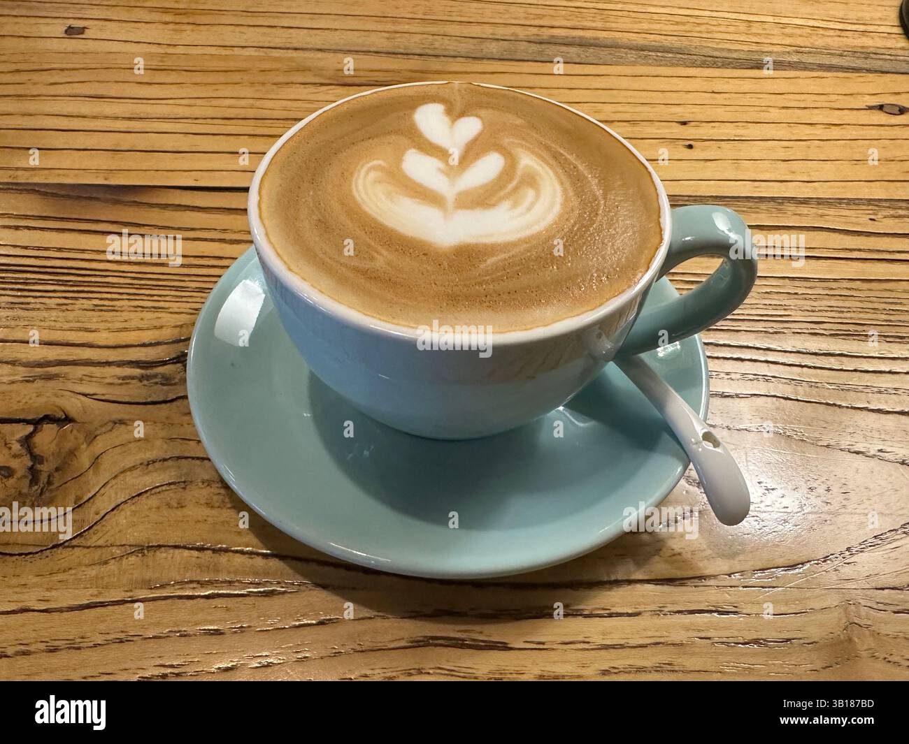 Creamy latte with heart-shaped art sits on a wooden table, ready to be enjoyed as a morning treat. - Smartphone Captured Stock Image