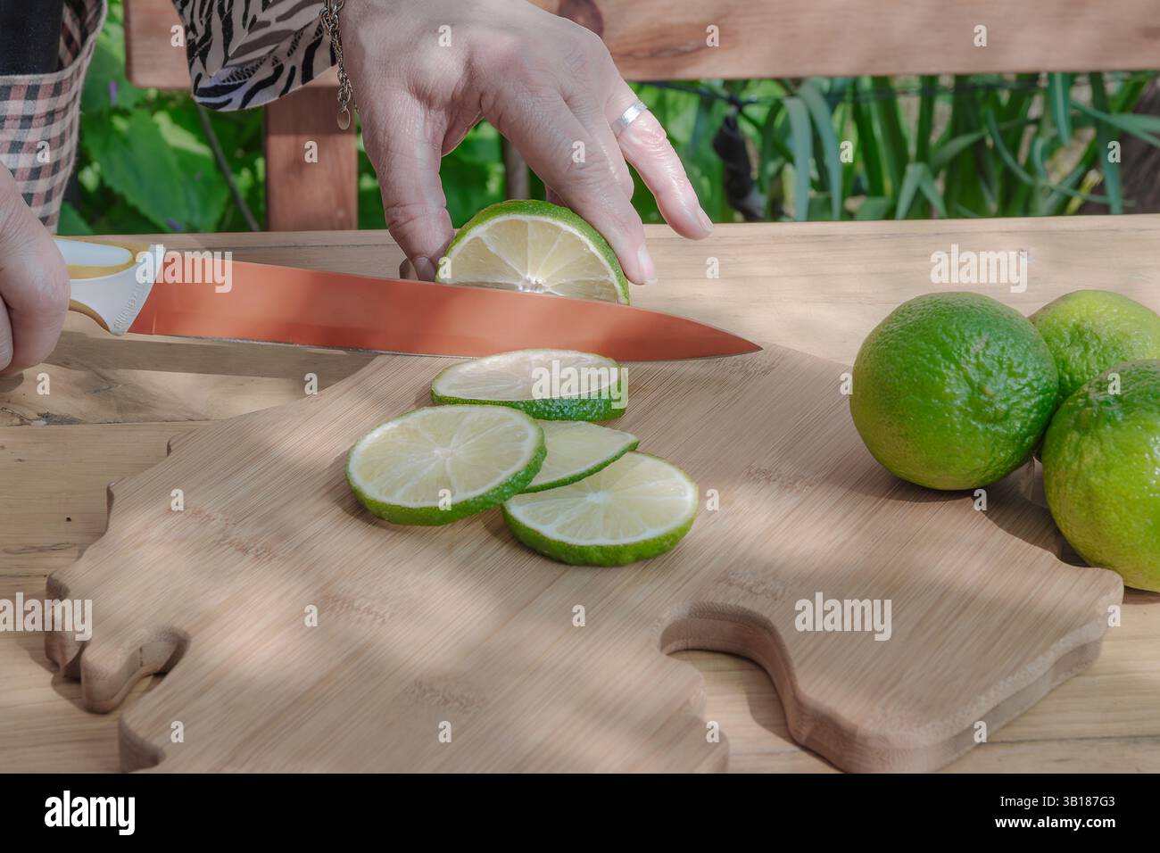 Slicing some limes with a knife on a cutting board. Stock Photo