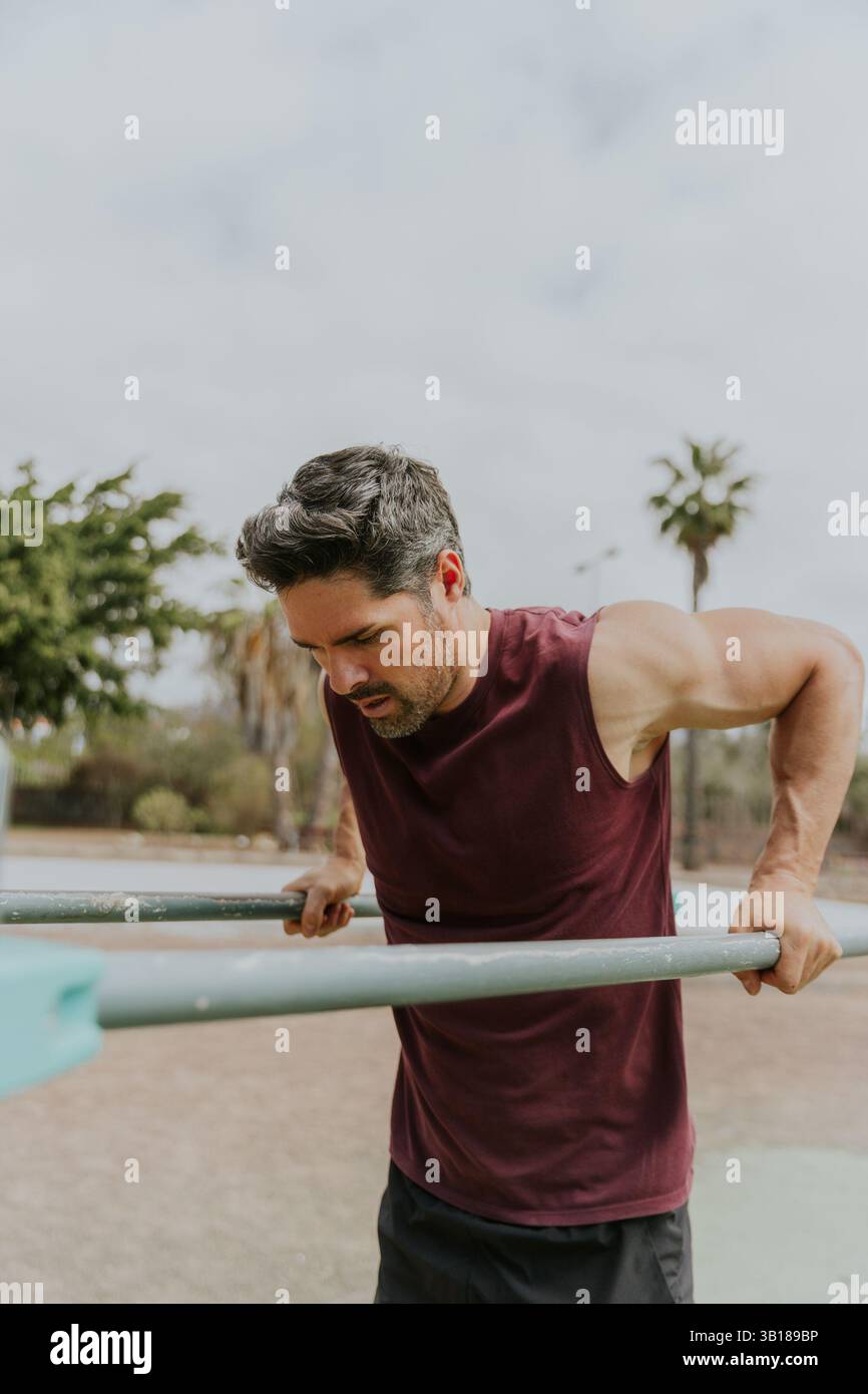 A concentrated man training, doing dips during a workout, vertical photo with copy space. Stock Photo