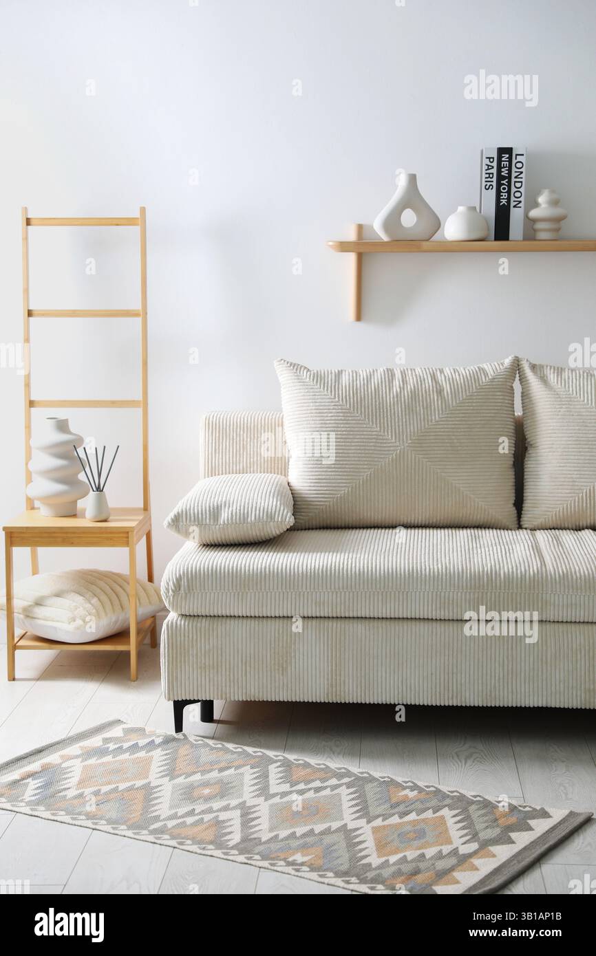 Comfortable sofa with pillows and different decor in room. Interior design Stock Photo