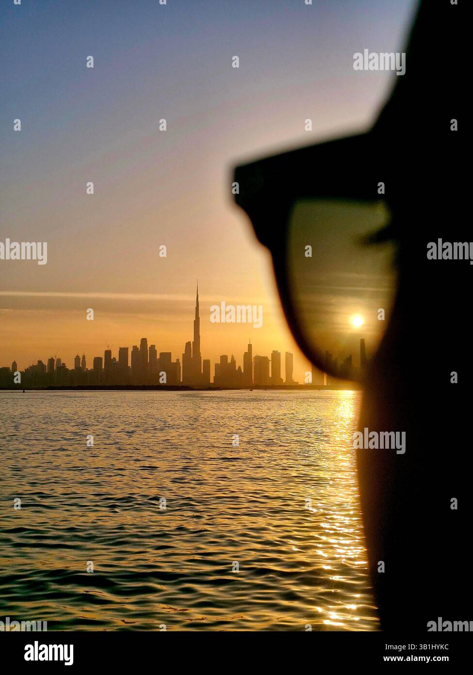Beautiful Dubai Creek Sunset, warm sky and skyline with Burj Khalifa background through sunglasses - Smartphone Captured Stock Image