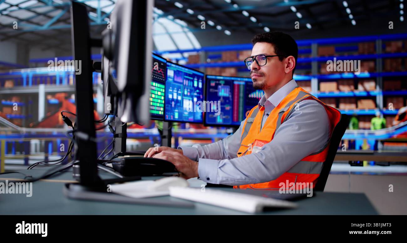 Hispanic Man Working At Computer In Warehouse Fulfillment Center Stock Photo