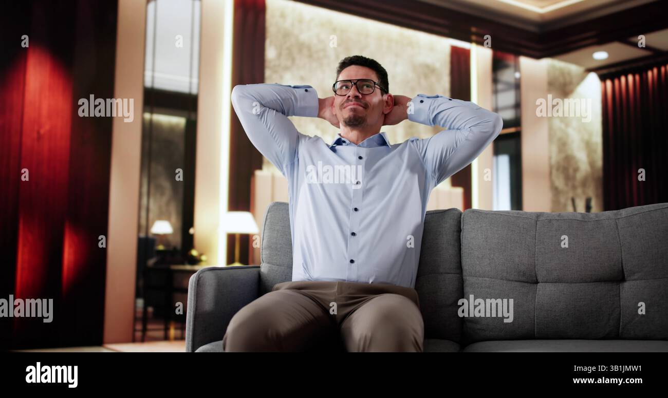 Happy Man Sitting On Sofa Thinking In Hotel Stock Photo