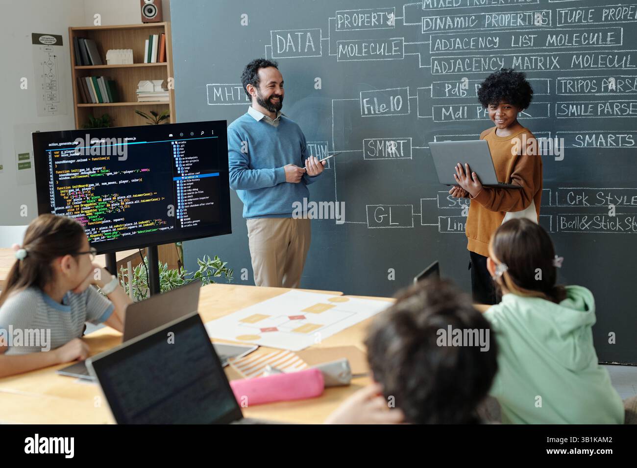 Teacher Explaining Programming Concepts to Engaged Students Stock Photo