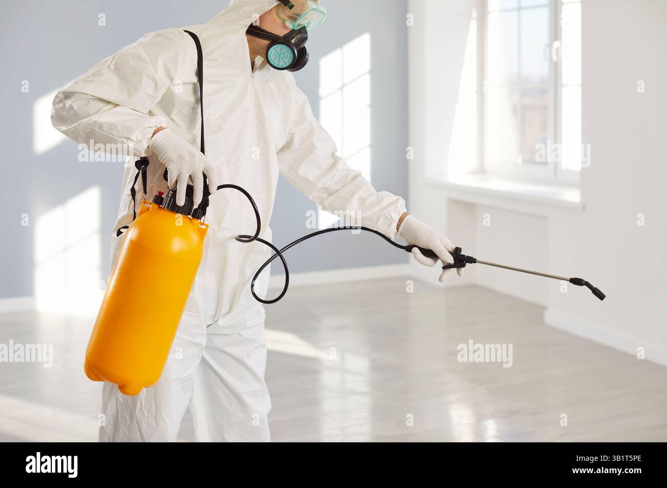 Exterminator service, worker in protective white coverall holding pump sprayer chemicals Stock Photo