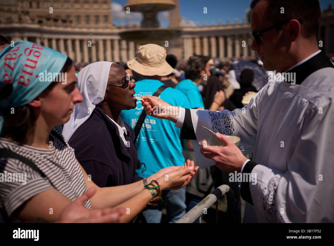A priest gives communion to a nun during the funeral of Pope Francis in ...