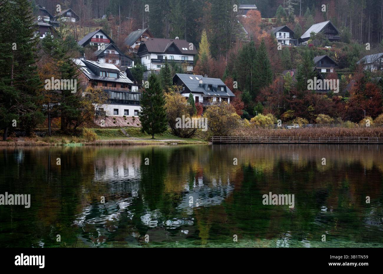 Beautiful alpine houses reflecting in a calm lake of jasna during autumn, creating a picturesque scene. Slovenia, Europe Stock Photo