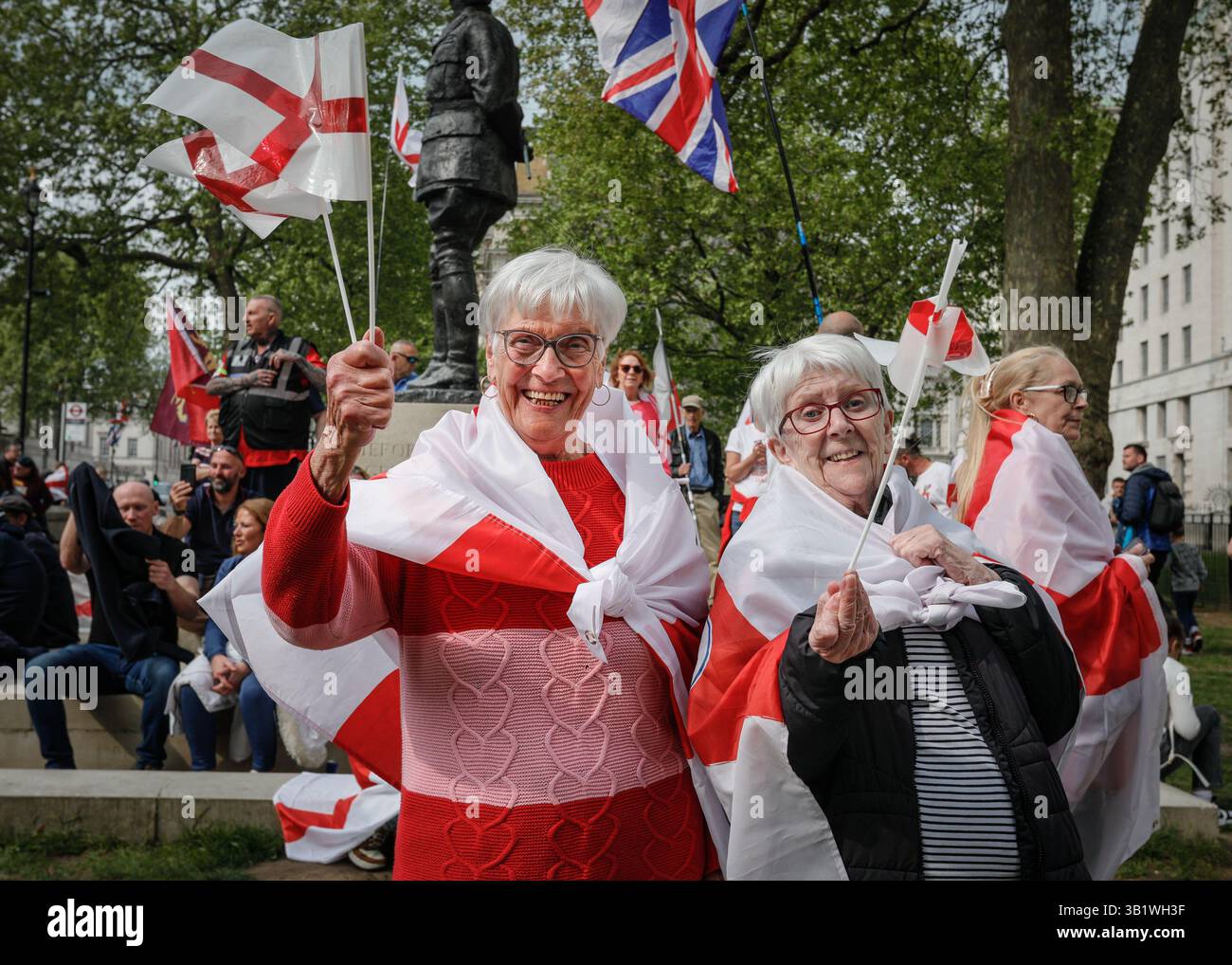 London, UK. 26th Apr, 2025. Two ladies enjoy their afternoon with St George's cross flags and outfits. A crowd of spectators decked out with England flags, and patriotic accessories have assembled opposite Downing Street in Whitehall to celebrate a ' St George's Day Festival' with speakers, performers and music. Some are in full St George's armour and costume. Several of the speakers take a more nationalist tone with political topics such as immigration on the agenda. Credit: News Ldn/Alamy Live News Stock Photo