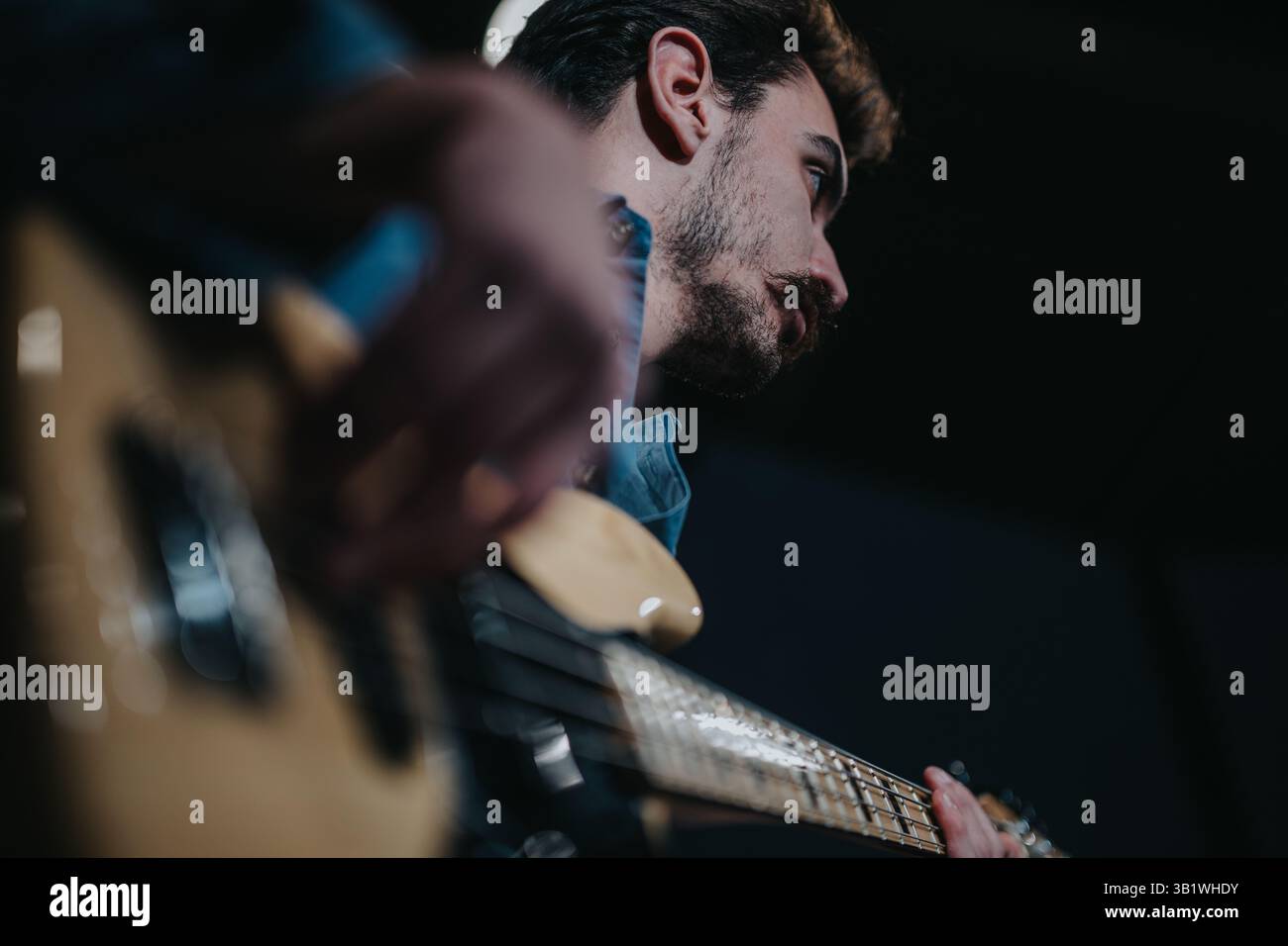 Close-up of a musician playing an electric guitar under stage lighting Stock Photo