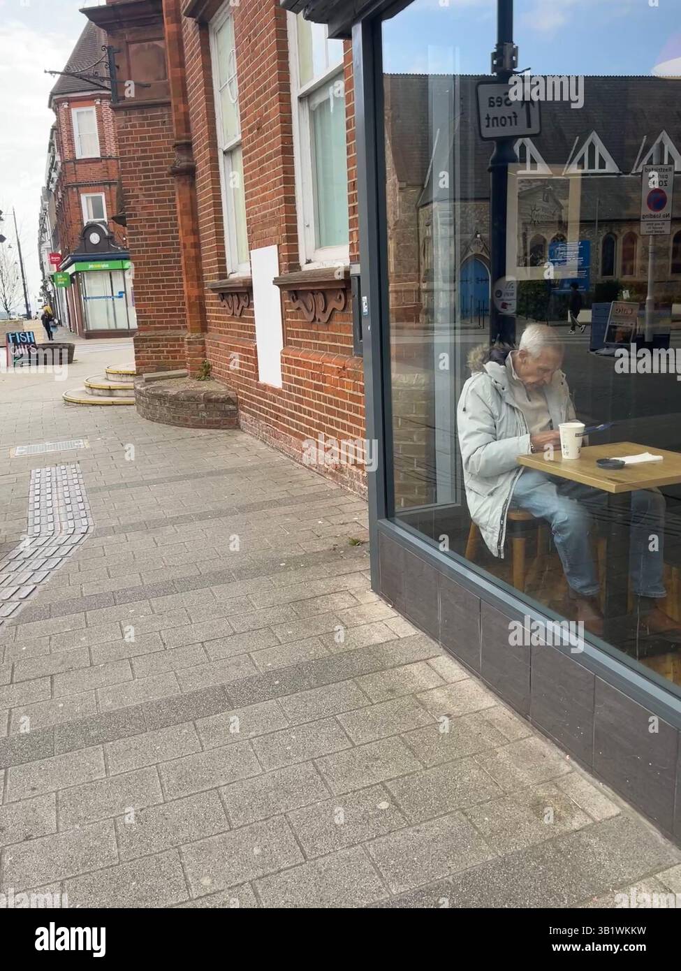 An elderly man seen through the window of a cafe in Felixstowe - Smartphone Captured Stock Image