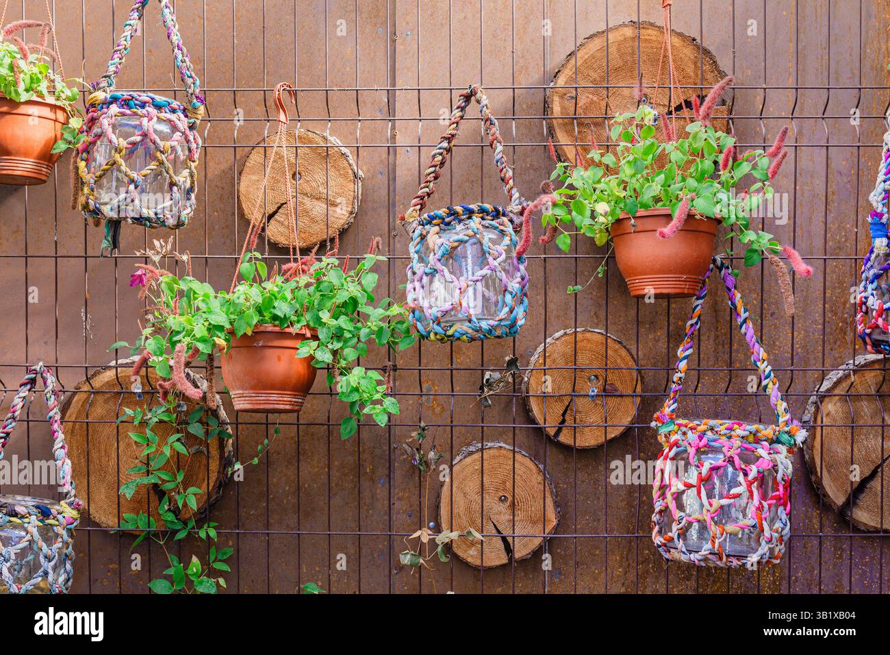 Plant pots and colorful rope macrame plant hangers hang from a wire ...