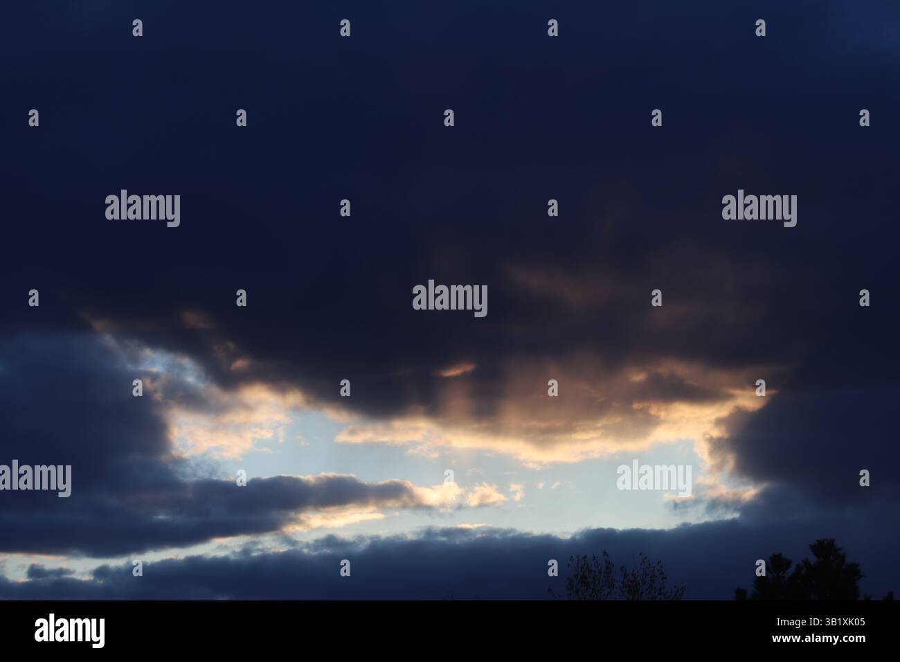 Crepuscular rays coming from a gap in the clouds during sunset Stock Photo