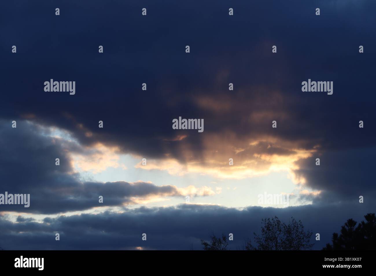 Crepuscular rays coming from a gap in the clouds during sunset Stock Photo