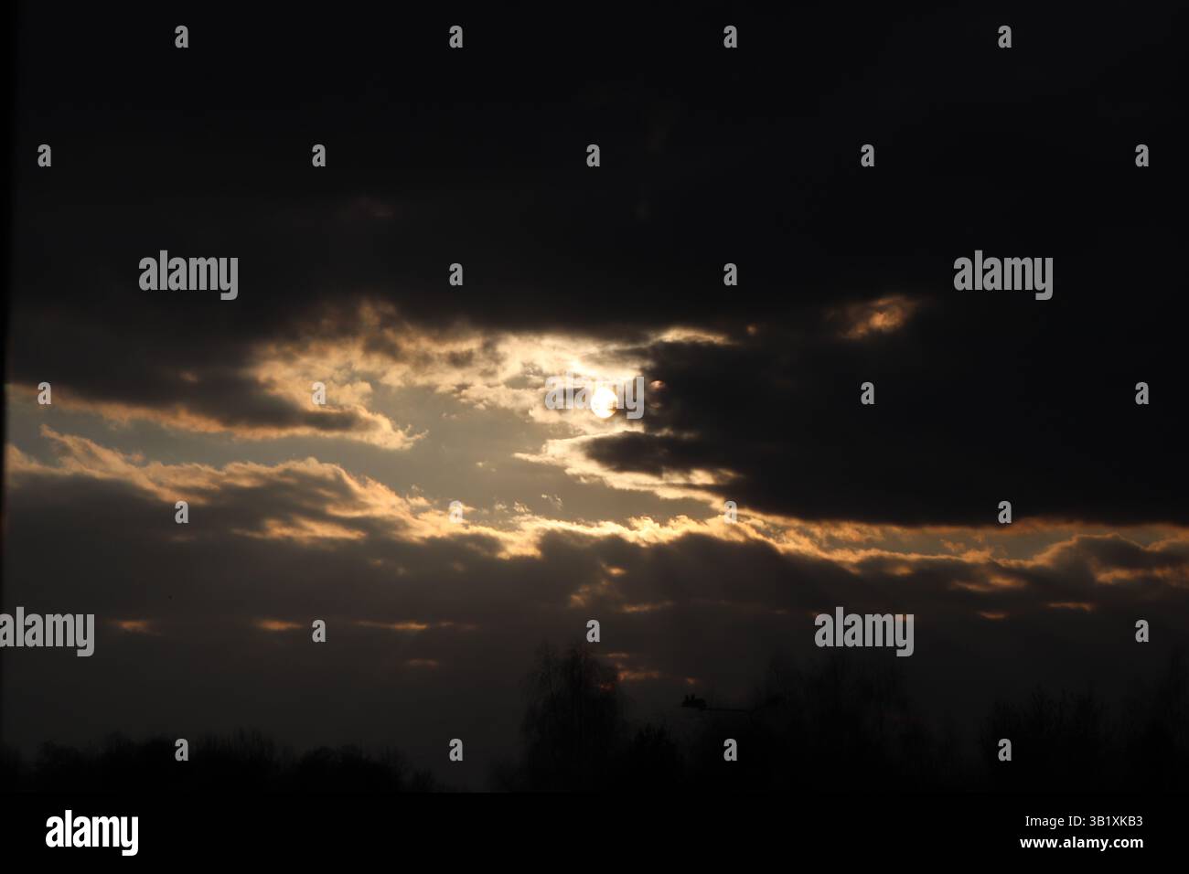 Sky covered by clouds during sunset with fight coming from a gap Stock Photo