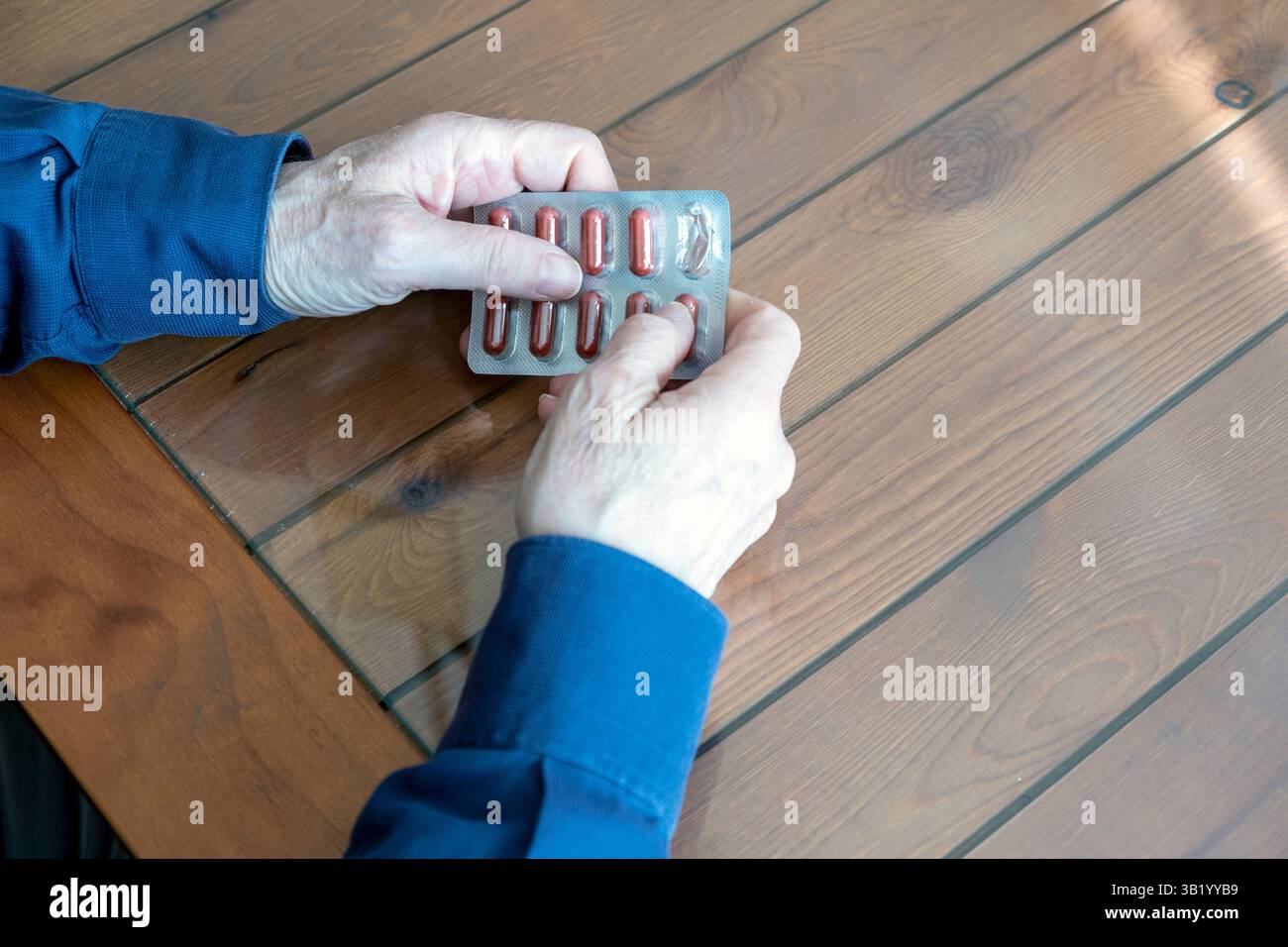 An elderly individual handling a blister pack of medicine capsules at a ...