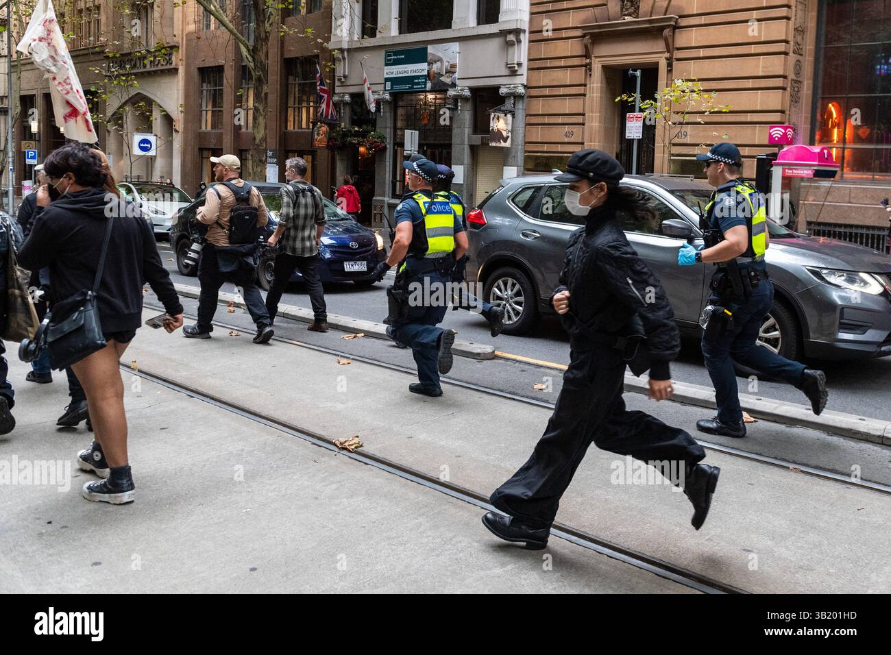Police and left-wing protesters run along Collins Street during post ...