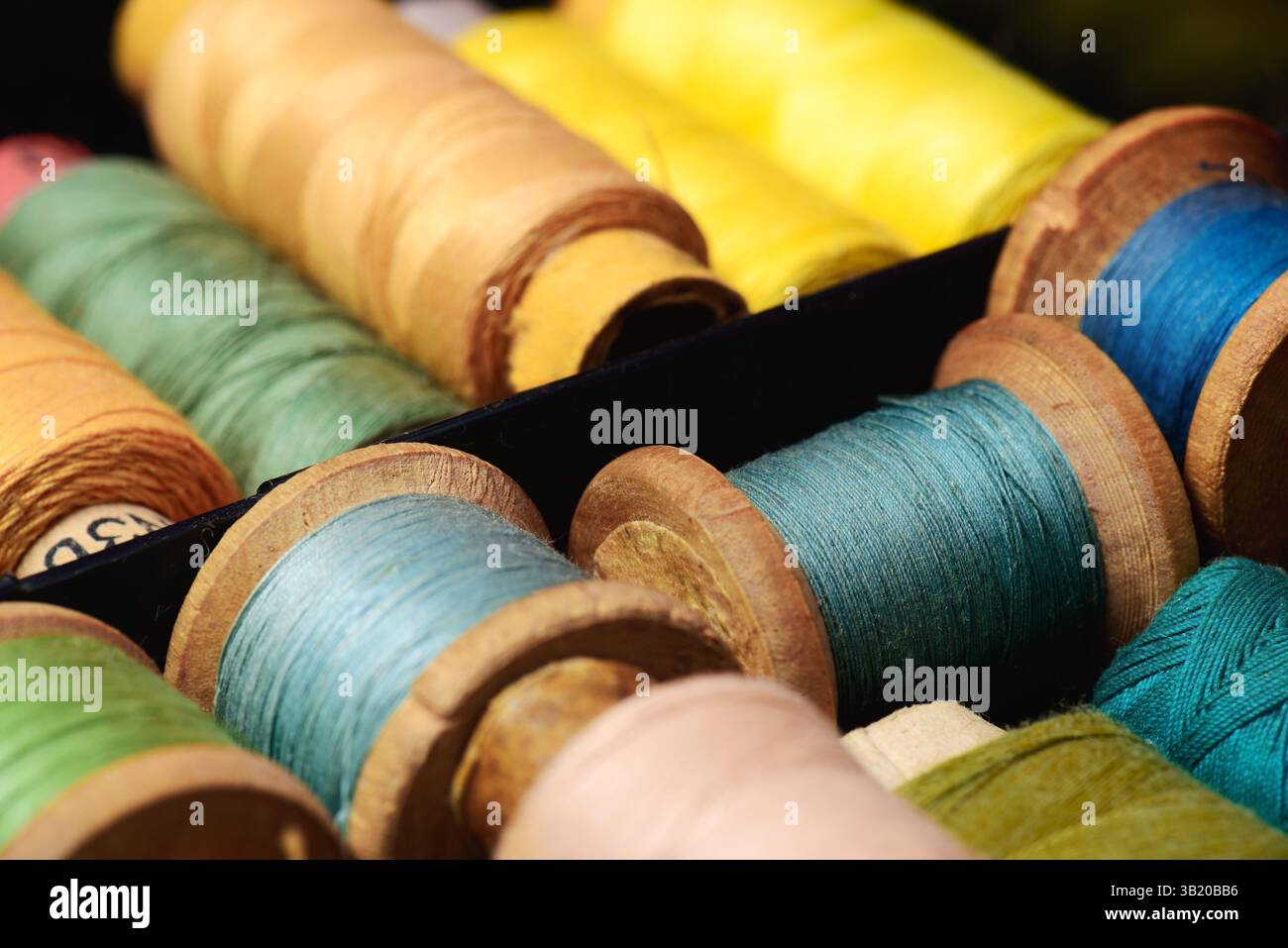 Lot of colored spools different sizes with thread in box closeup Stock Photo