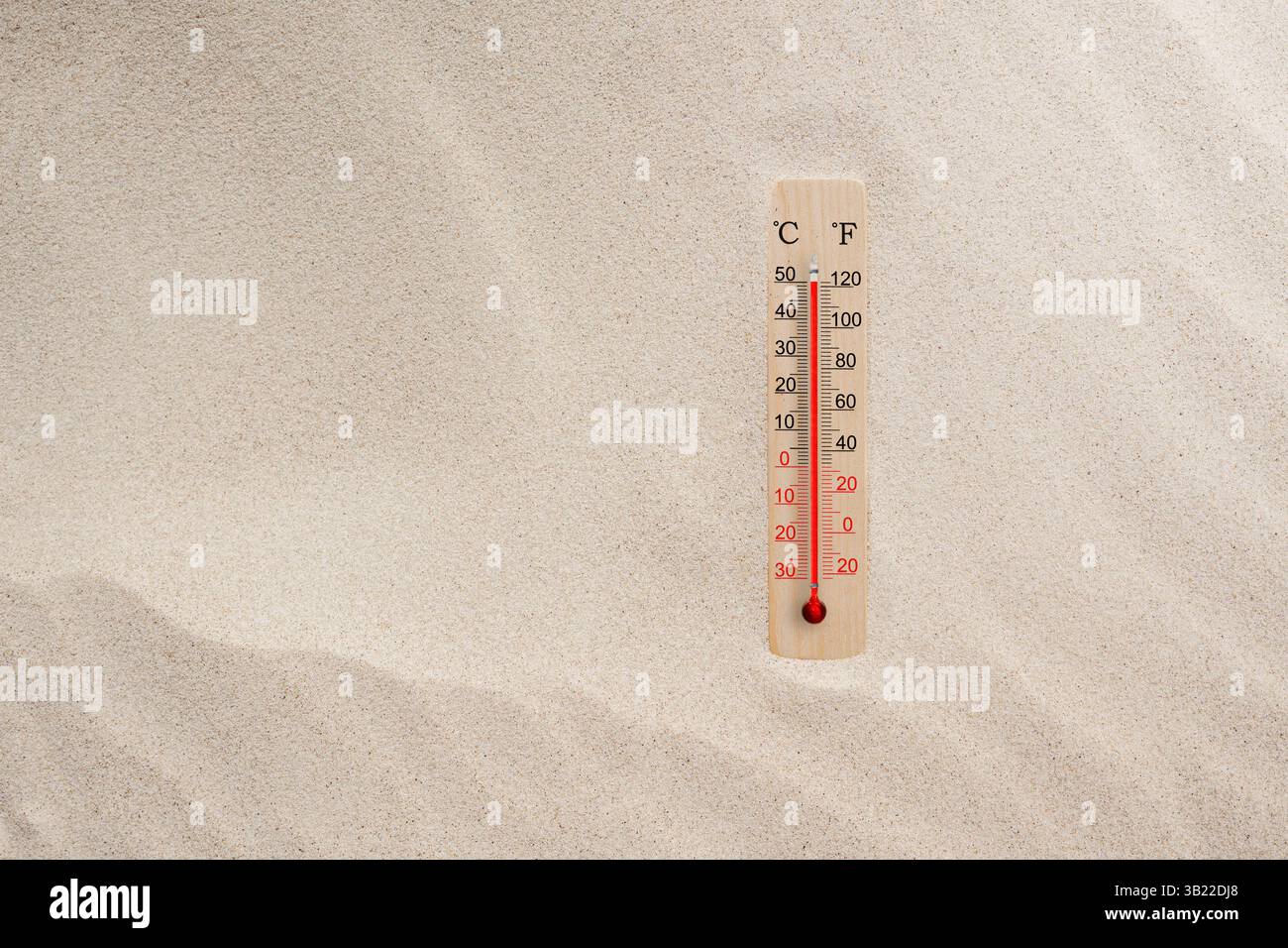 Wooden celsius and fahrenheit scale thermometer in the sand. Ambient temperature plus 50 degrees. Hot summer day Stock Photo