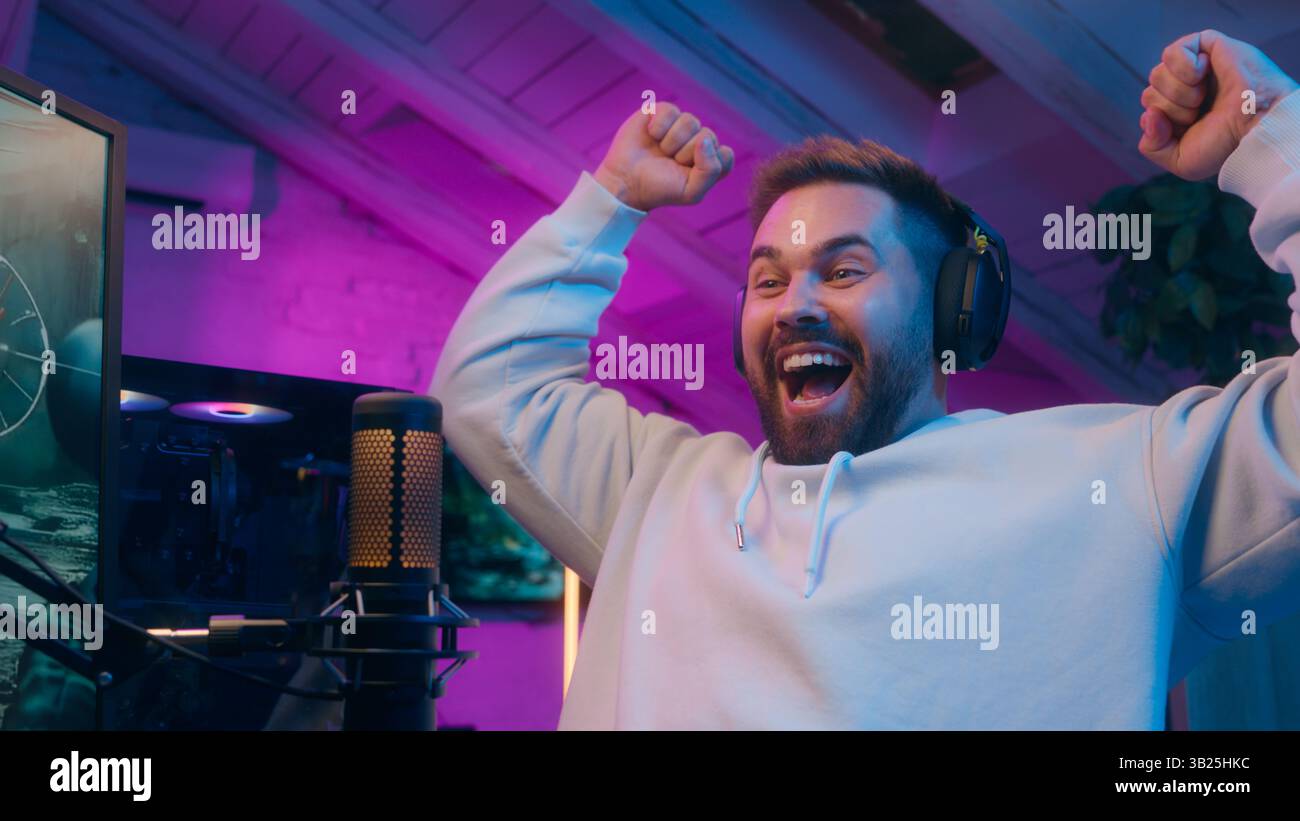 Joyful Caucasian male guy gamer streamer playing computer tech e-sport at home man winning shout winner rejoice addict influencer celebrate game Stock Photo
