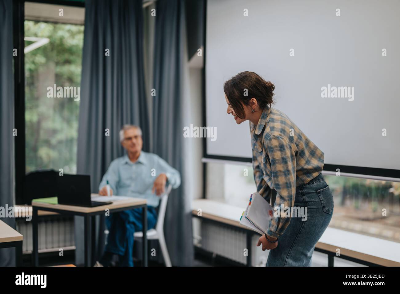 Students in a classroom engaging with an elderly professor Stock Photo