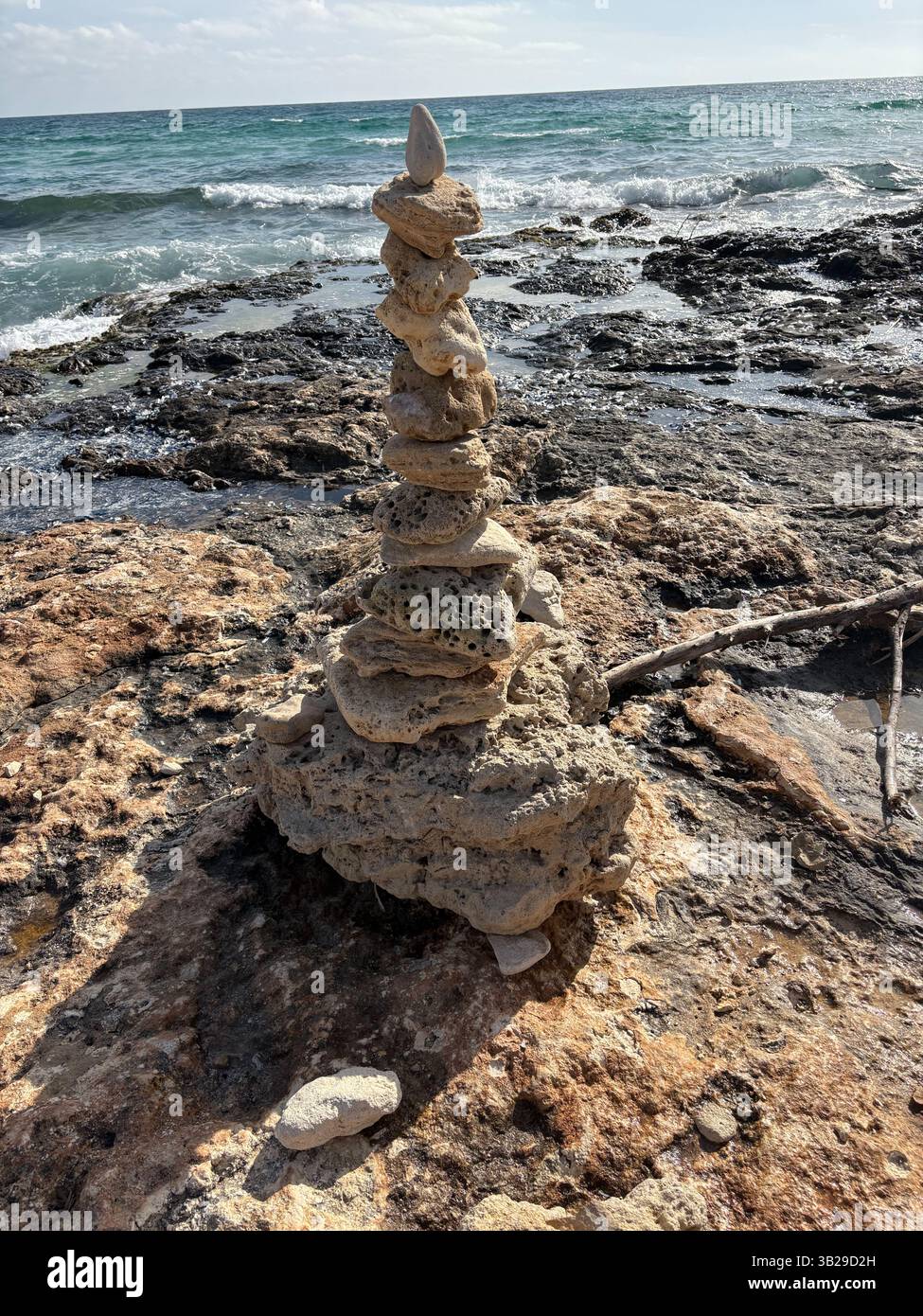 Handmade Free Standing Stone Tower on a Beach With Calm Sea and Blue Sky With White Fluffy Clouds - Smartphone Captured Stock Image