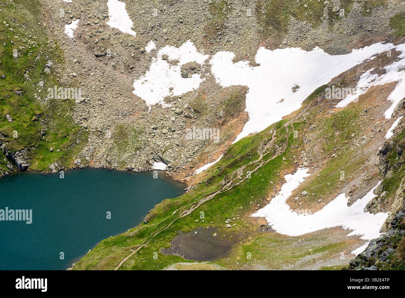 capra lake of fagaras ridge in summer. pristine remote torrent. rippled water surface and grass on the shore view from above. alpine pond carpathian m Stock Photo