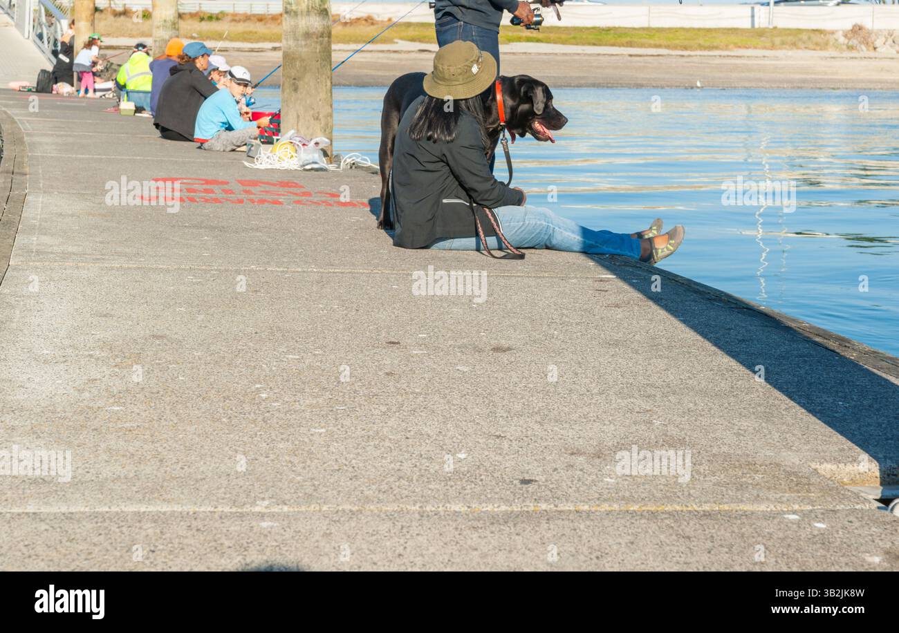 Tauranga New Zealand - April 22 2012; Fishing with dog on pier at Bridge Marina. 2012; Fishing with dog on pier at Bridge Marina. Stock Photo