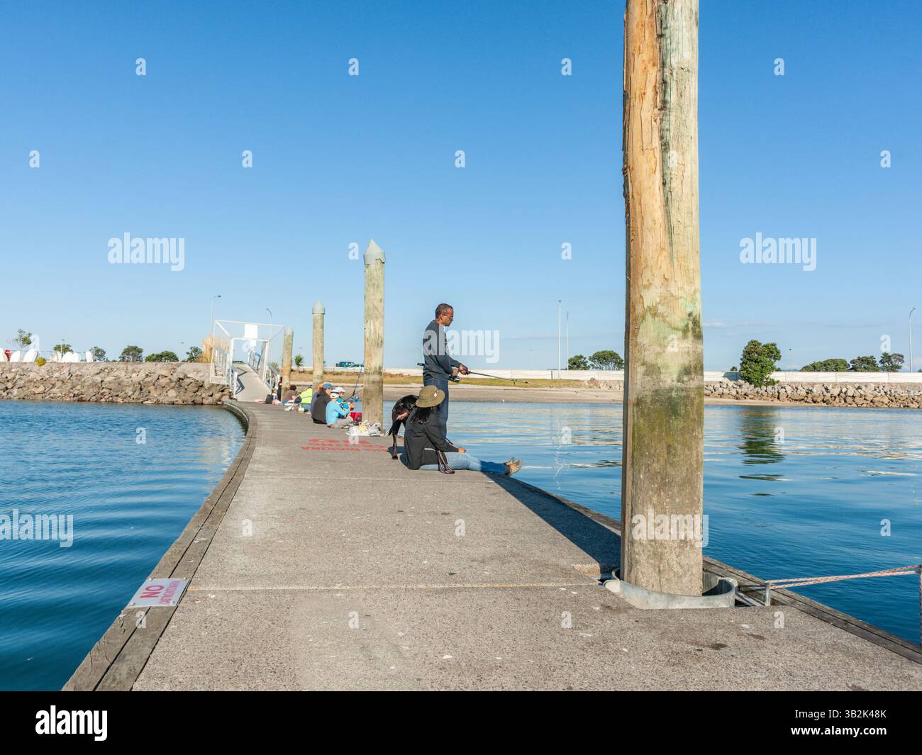 Tauranga New Zealand - April 22 2012; Fishing with dog on pier at Bridge Marina. 2012; Fishing with dog on pier at Bridge Marina. Stock Photo