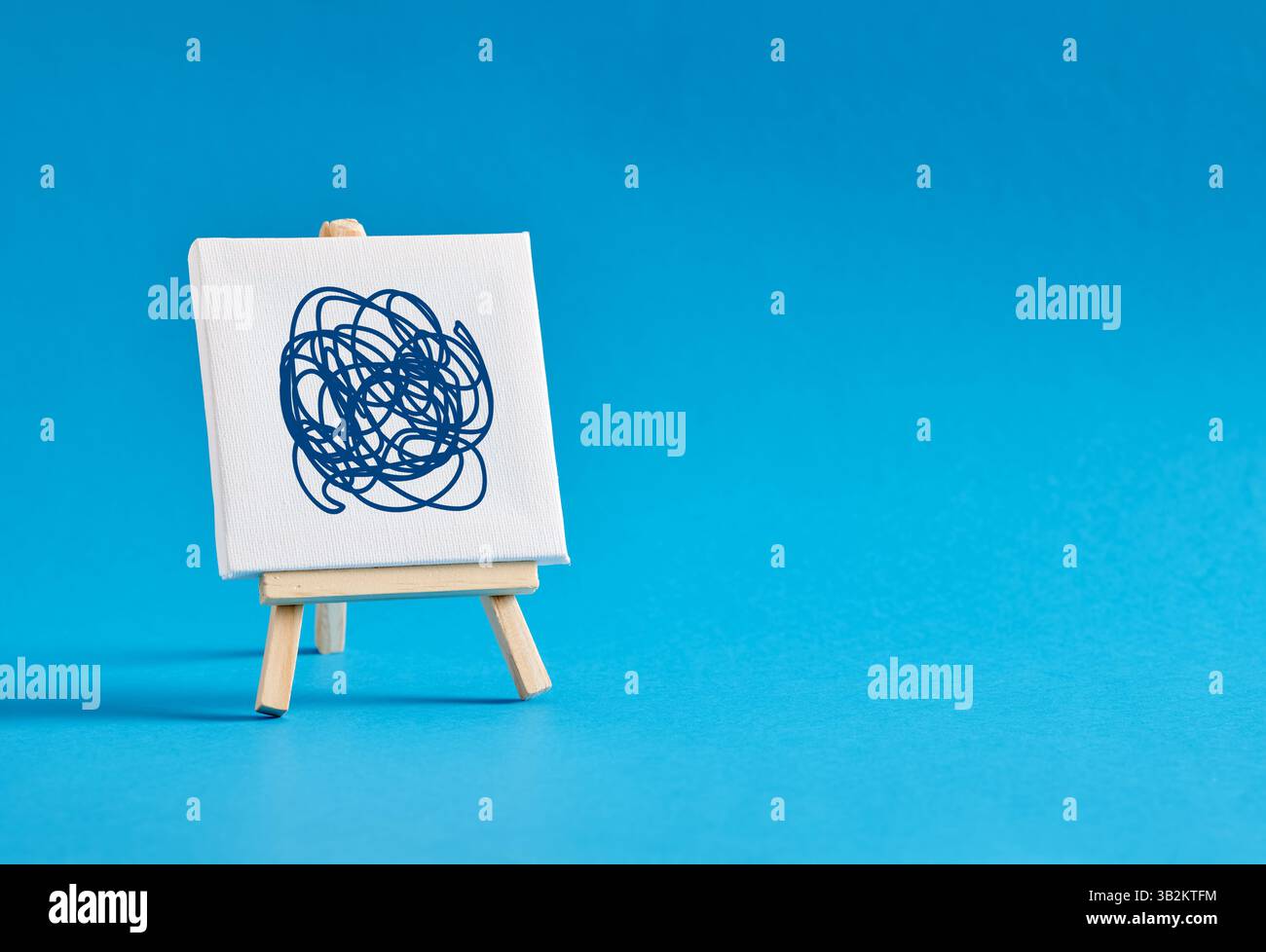 Easel with a tangled scribble on blue background. Complication, complexity, messy, chaos and mental disorder concepts. Stock Photo