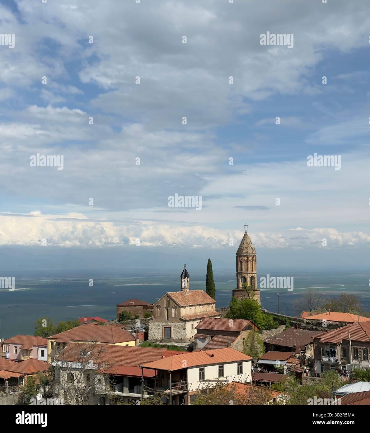 Scenic historic town with red-tiled rooftops and towering churches, set against rolling hills. Perfect for themes of travel, architecture, and Europea - Smartphone Captured Stock Image