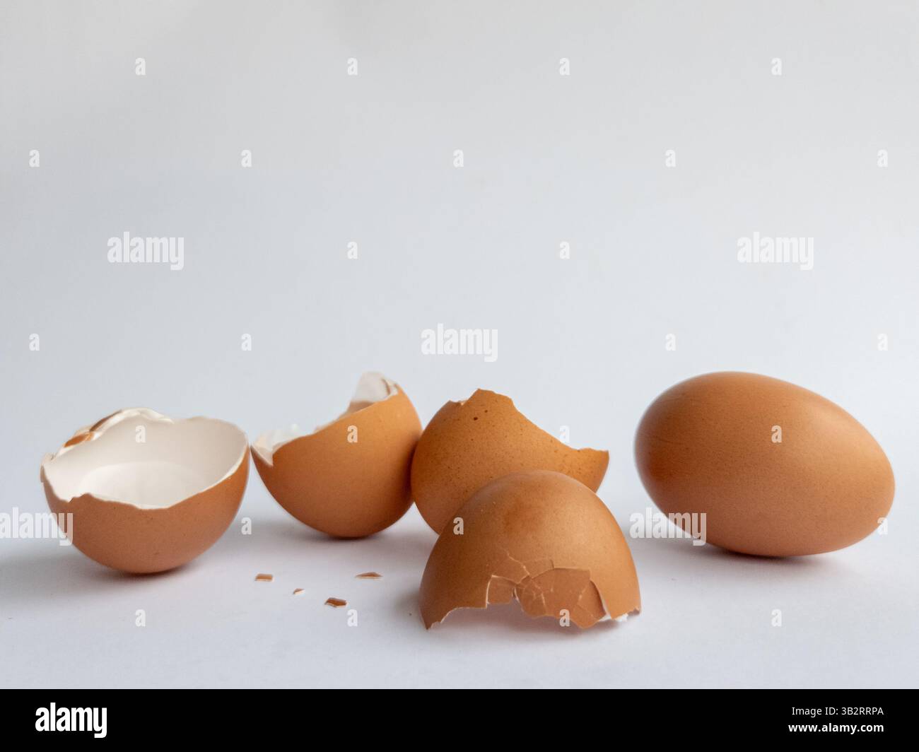Broken eggshells and whole egg on white background close up view - Smartphone Captured Stock Image