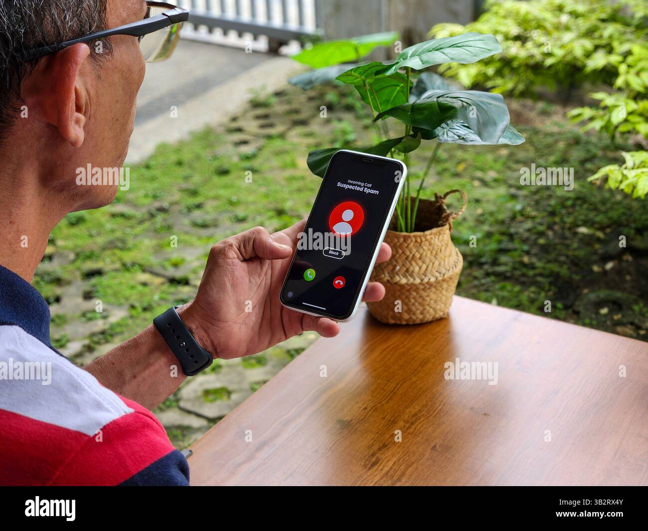 Man receives suspected spam call on phone outdoors in daytime - Smartphone Captured Stock Image