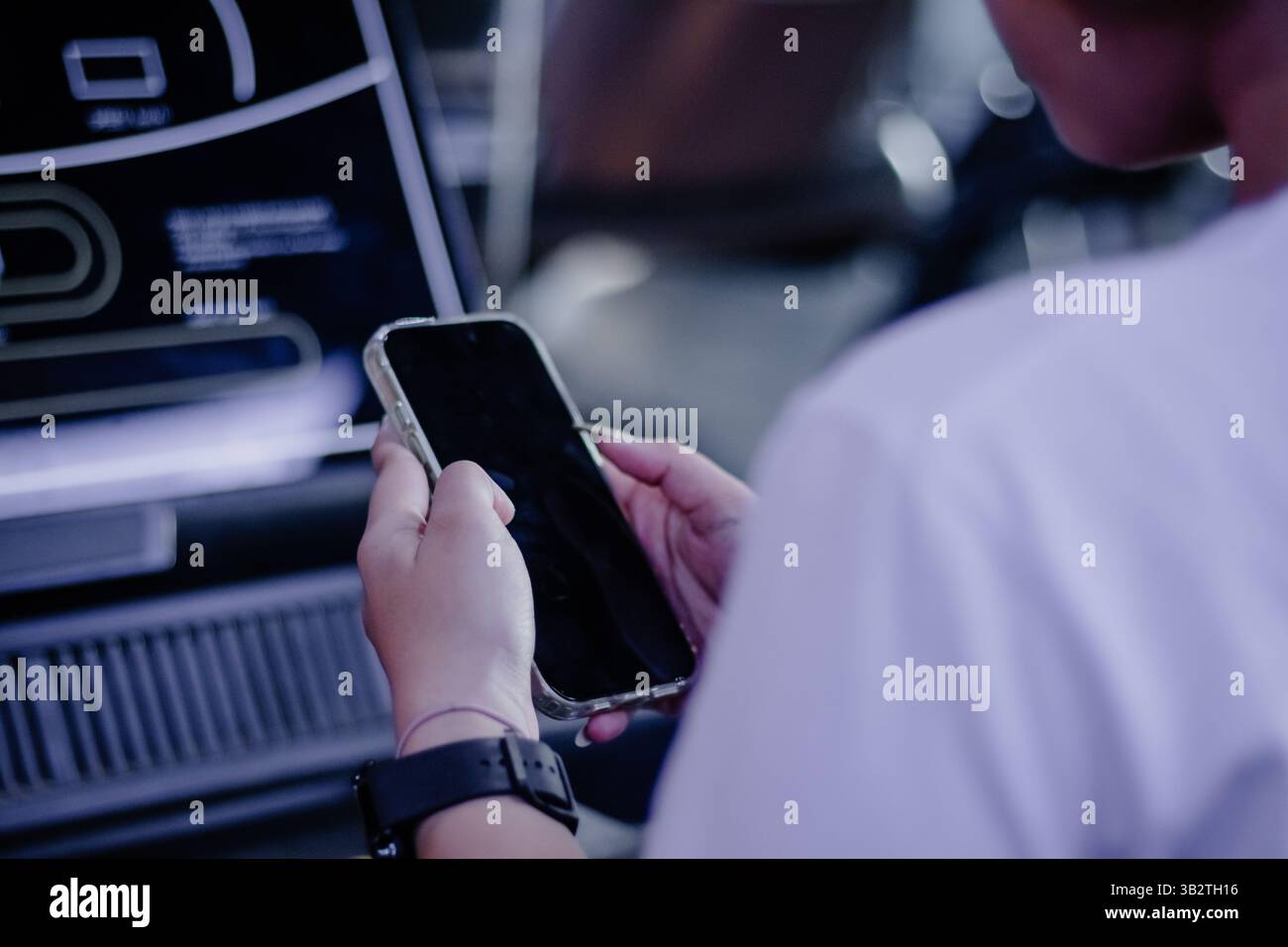 A person interacts with a digital display screen using mobile technology, suggesting modern connectivity, interactive interfaces, and digital innovati Stock Photo