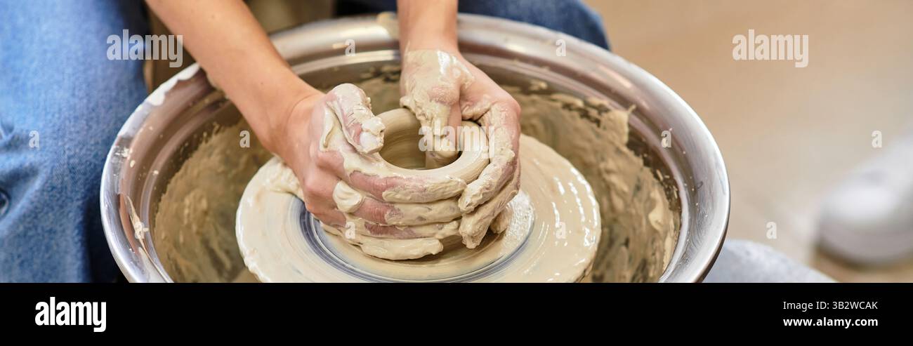 Hands work skillfully with clay on a pottery wheel, shaping a ...