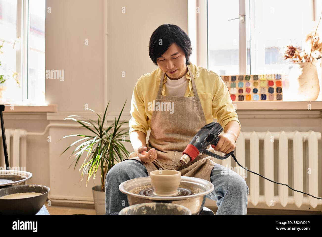 An artist skillfully shapes pottery in a bright studio filled with ...