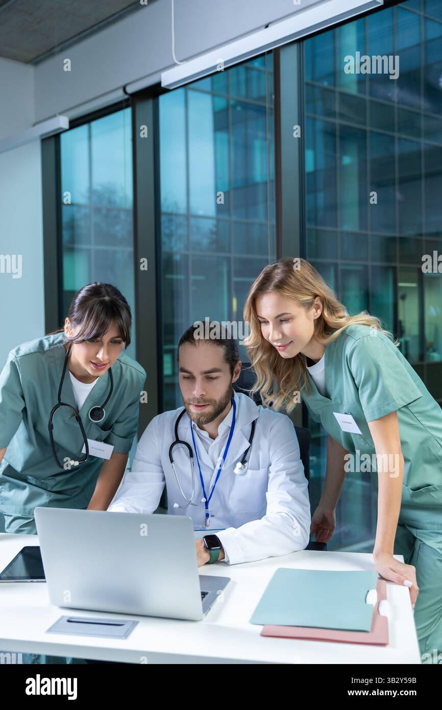 Doctors practitioners in hospital discussing care plan using digital tools Stock Photo