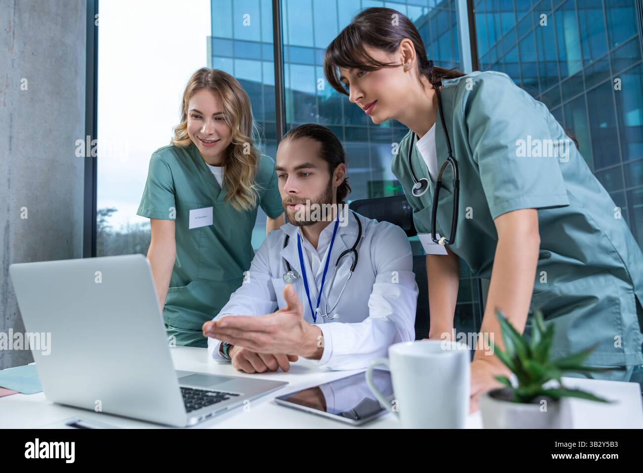 Doctors practitioners in hospital discussing care plan using digital tools Stock Photo