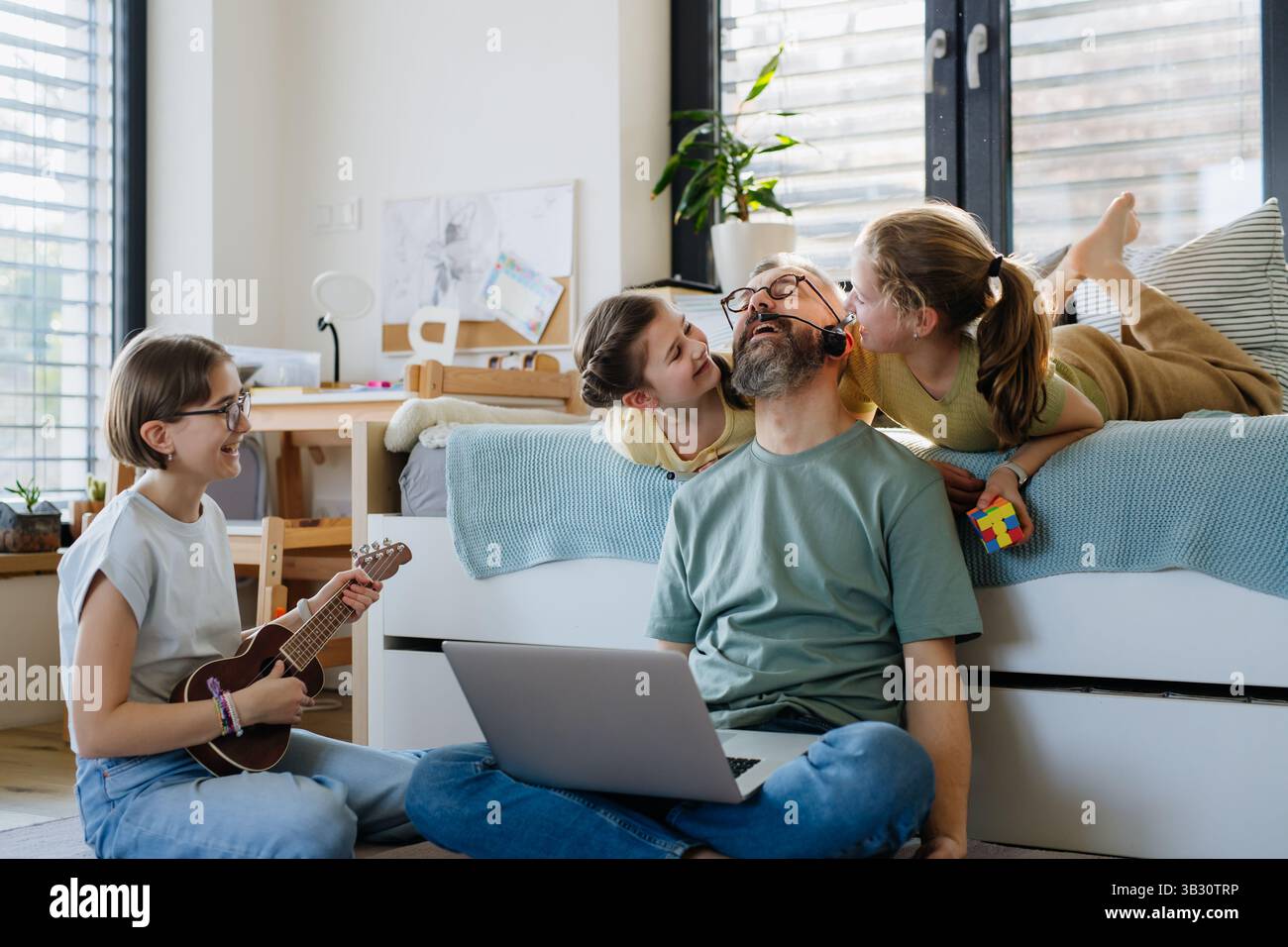 Father with three daughters trying to work from homeoffice. Stock Photo