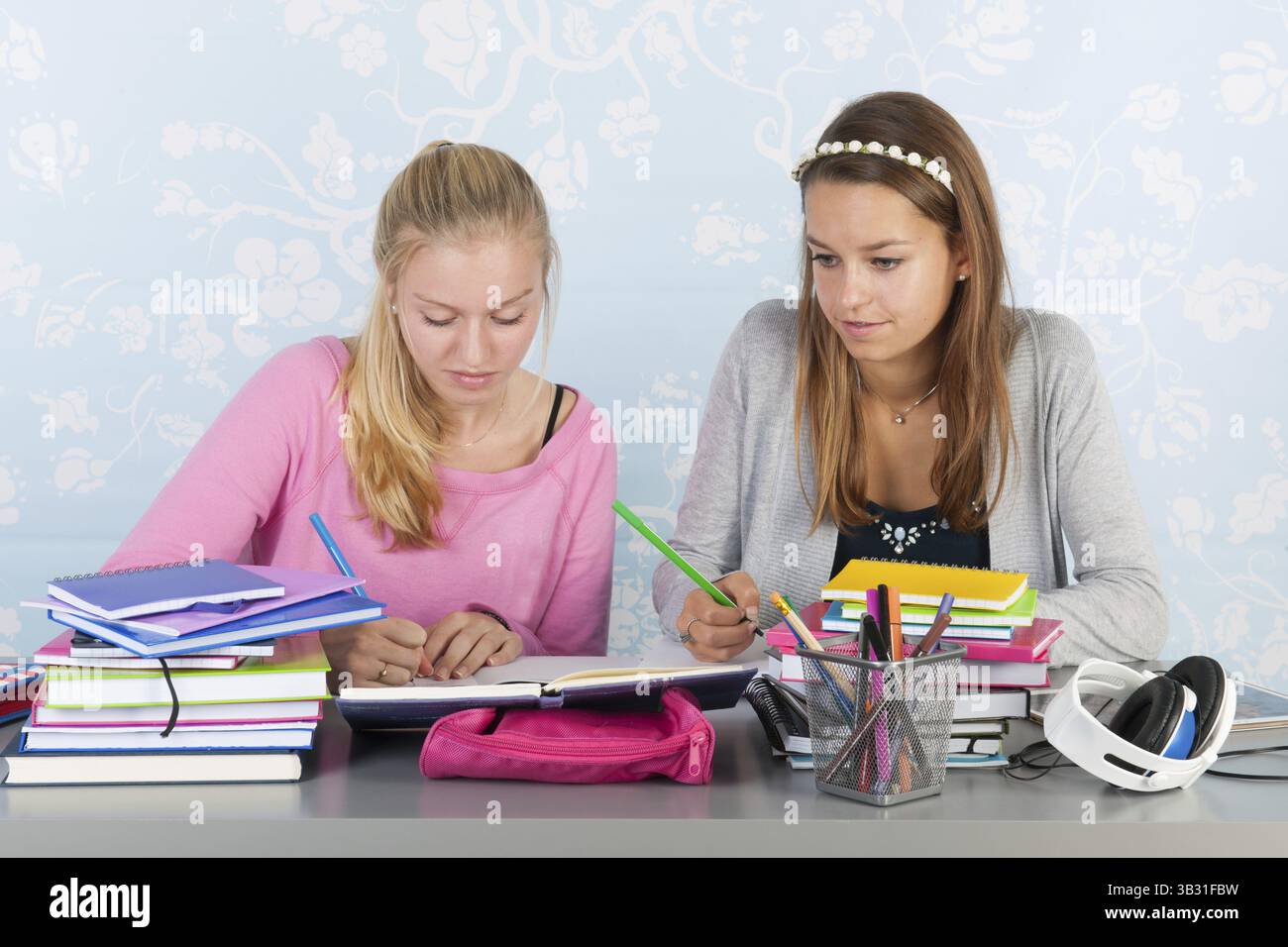 Two teengirls sitting at desk making homework together Stock Photo